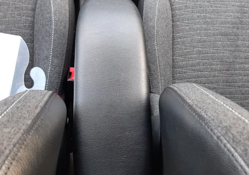 Vue plongeante sur l'accoudoir central noir entre les sièges avant gris tissu de la Citroën C3 BlueHDi 2016.