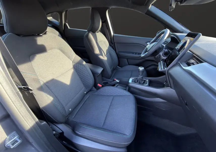 Vue intérieure côté conducteur du Renault Captur 2024 gris Cassiopée, montrant les sièges et la console avec boîte manuelle.