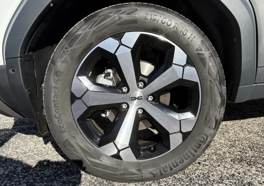 Gros plan sur la roue arrière droite d'un Dacia Duster blanc métallisé 2024 avec passage de roue noir.