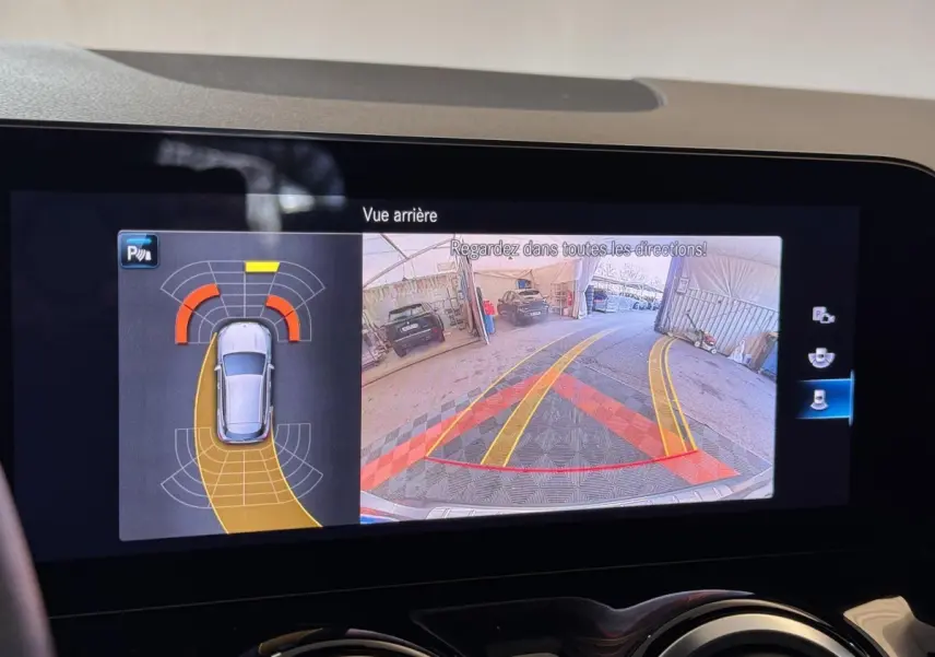 Écran tactile intérieur montrant la caméra de recul et l’aide au stationnement du Mercedes GLA 250 e gris foncé.