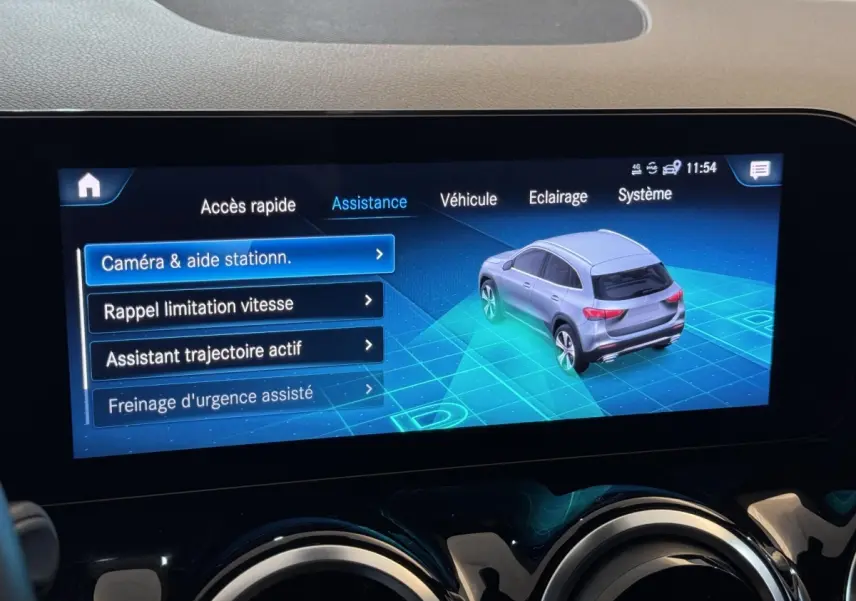 Écran tactile intérieur montrant l'assistance au stationnement avec une vue 3/4 arrière virtuelle du Mercedes GLA gris foncé.
