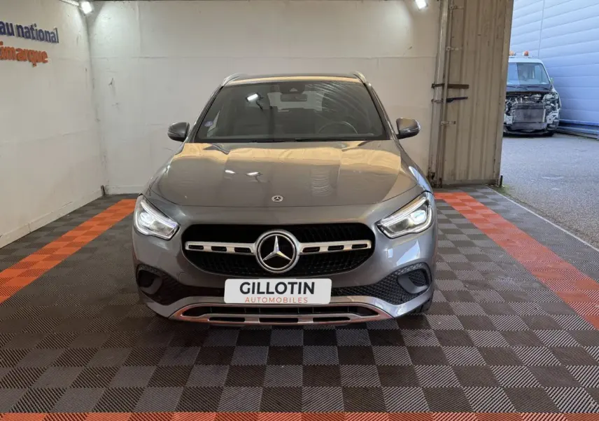 Vue avant d'une Mercedes GLA 250 e Business Line gris foncé avec calandre et phares LED allumés, dans un garage.
