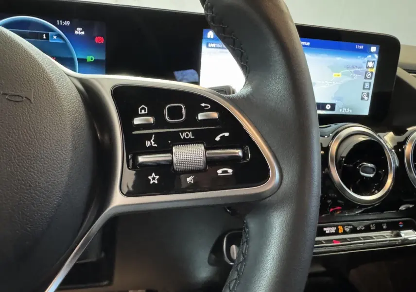 Gros plan sur le volant cuir multifonctions et les écrans tactiles du tableau de bord du Mercedes GLA 250 e gris foncé.