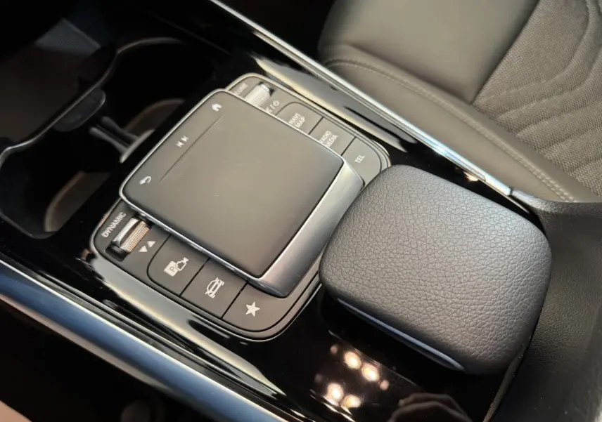 Gros plan sur la console centrale noire avec pavé tactile et accoudoir cuir gris du Mercedes GLA 250 e Business Line 2023.
