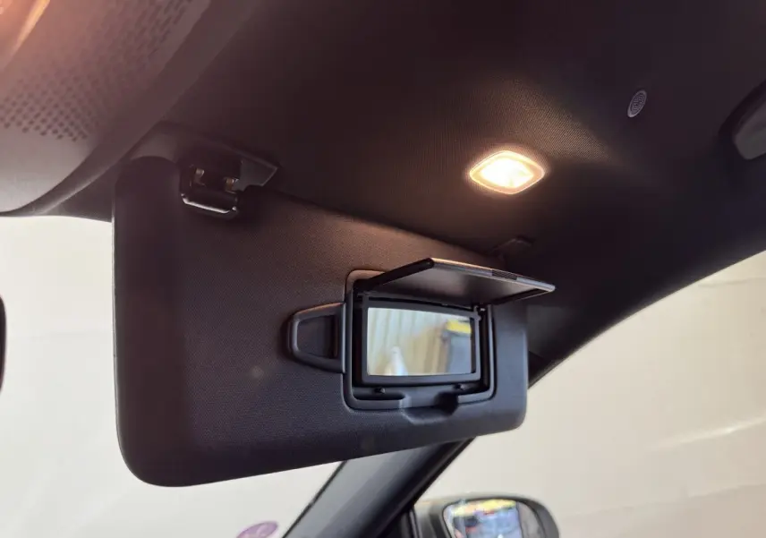 Détail du pare-soleil côté conducteur avec miroir éclairé dans l’habitacle sombre d’une Mercedes GLA 250 e gris foncé.