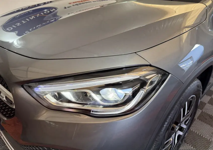Gros plan sur le phare avant droit du Mercedes GLA 250 e Business Line gris foncé, soulignant ses détails LED modernes.