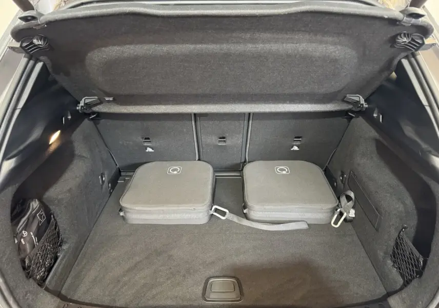 Coffre ouvert vu de face d’un Mercedes GLA 250 e Business Line gris foncé avec deux valises de recharge posées.