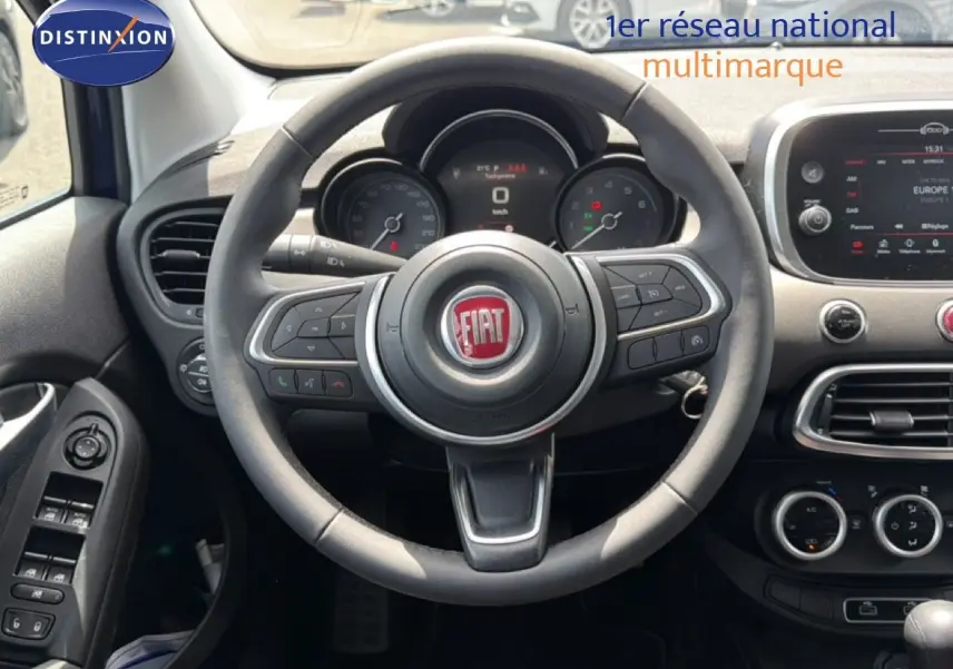 Vue intérieure centrée sur le volant du Fiat 500X 2024, avec tableau de bord et écran tactile visibles.