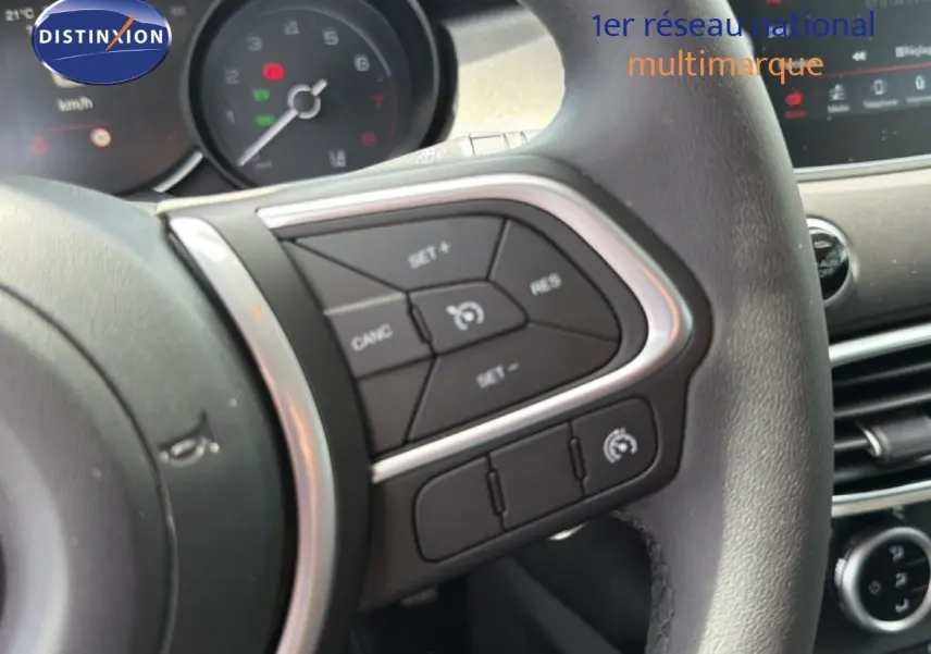 Gros plan sur le volant côté gauche du Fiat 500X 2024 avec commandes de régulateur de vitesse et tableau de bord partiel.