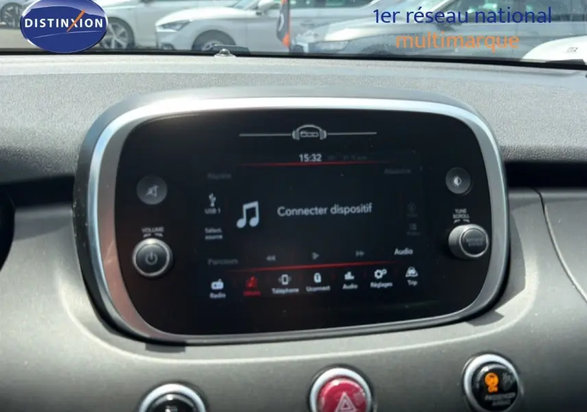 Écran tactile central du tableau de bord de la FIAT 500X 2024 avec commandes audio et climatisation visibles.
