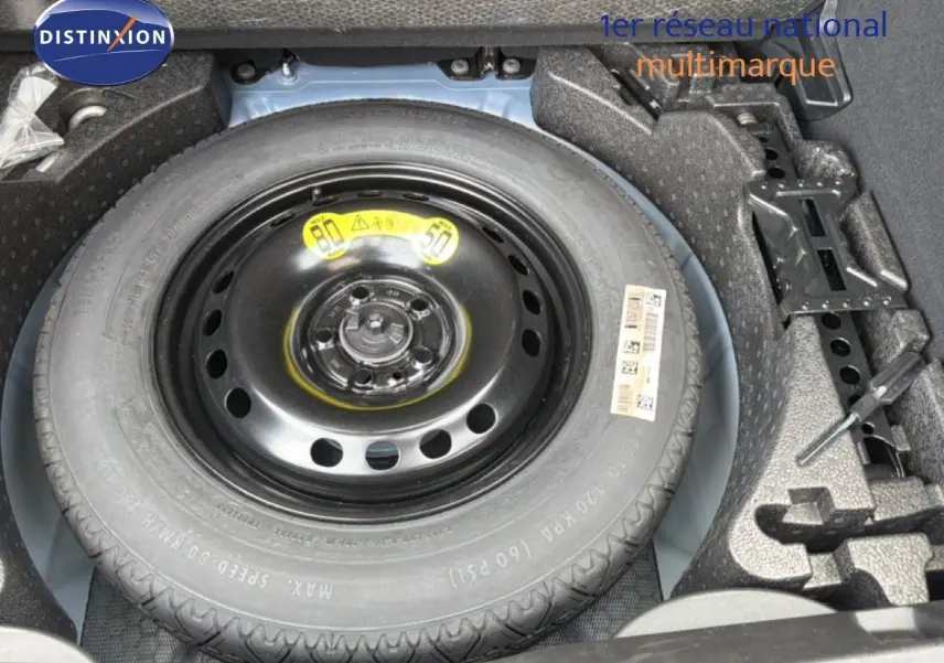 Vue rapprochée de la roue de secours noire dans le coffre d'une FIAT 500X Bleu Venezia 2024.