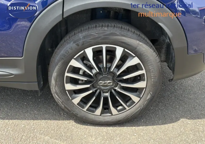 Gros plan sur la roue avant droite d'une FIAT 500X bleu Venezia avec jante alliage bicolore et logo central.