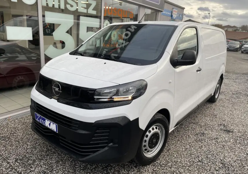 Vue 3/4 avant droite d’un Opel Vivaro blanc avec calandre noire et jantes tôles grises, stationné devant un showroom.