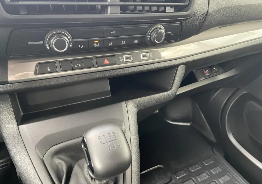 Intérieur Opel Vivaro 2024 vue côté passager, console centrale avec levier de vitesses manuel et commandes climatisation.