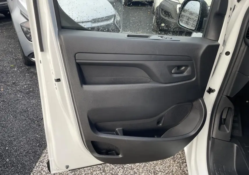 Vue intérieure de la porte avant gauche blanche d’un Opel Vivaro 2024 avec panneau de porte noir et poignée intégrée.
