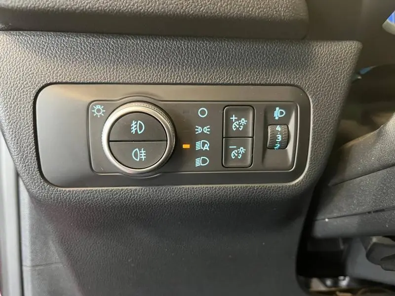 Gros plan sur les commandes d'éclairage intérieures noires du Ford Kuga 2022, avec réglage des phares et feux antibrouillard.