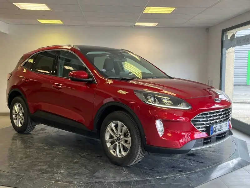 Ford Kuga rouge Premium Lucid vu en 3/4 avant droit avec toit panoramique dans un showroom.