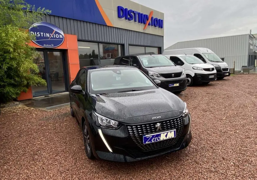 Peugeot 208 noir métallisé vue 3/4 avant sur parking devant concession Distinxion par temps pluvieux.