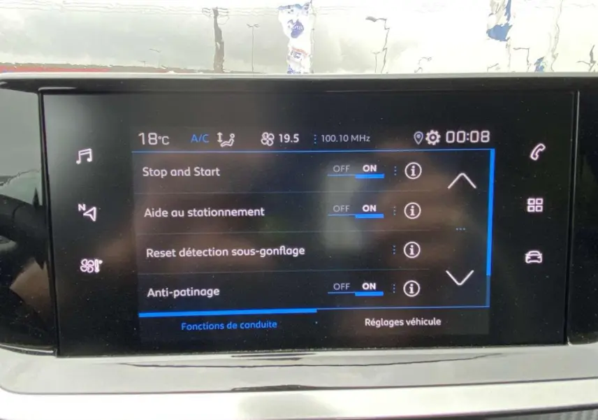 Écran tactile central de la Peugeot 208 noir métallisé affichant les réglages d’aide au stationnement et conduite.
