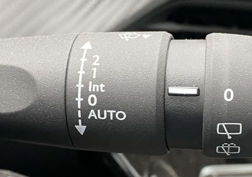 Gros plan sur la commande d’essuie-glace automatique du Peugeot 208 noir métallisé, version 2023 Allure.
