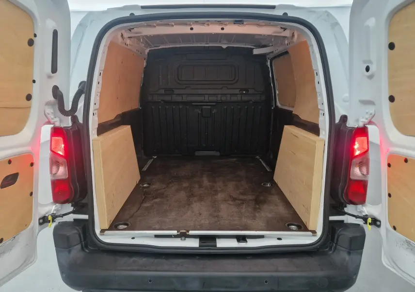 Vue arrière ouverte du Citroën Berlingo blanc 2019 montrant l'espace de chargement avec habillage bois et plancher sombre.