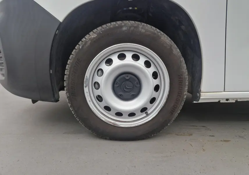 Gros plan sur la roue avant gauche d'un Citroën Berlingo blanc de 2019 avec jante acier et logo Citroën central.