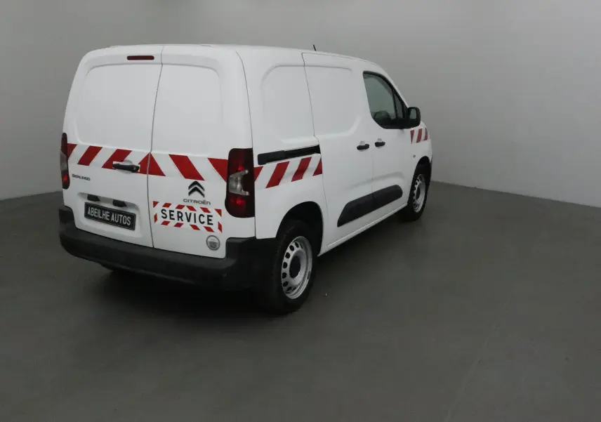 Vue 3/4 arrière droite d’un utilitaire blanc Citroën Berlingo avec bandes rouges diagonales et logo Service.