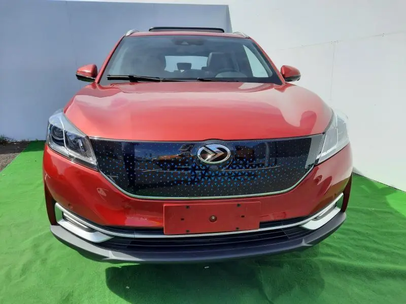 Vue avant d'un SUV électrique SERES 3 rouge carmin avec calandre noire à motifs bleus et toit panoramique visible.