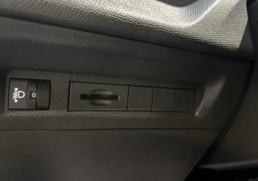 Détail des commandes d’éclairage et réglage du tableau de bord sur la porte côté conducteur d’un Peugeot 308 SW gris clair.