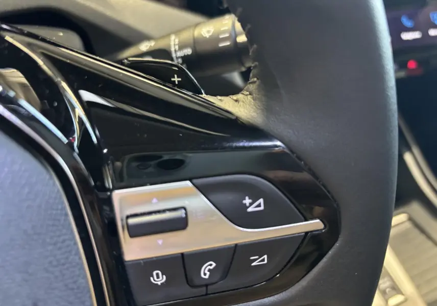Gros plan sur les commandes multifonctions noires et chromées du volant cuir de la Peugeot 308 SW gris clair métallisé.