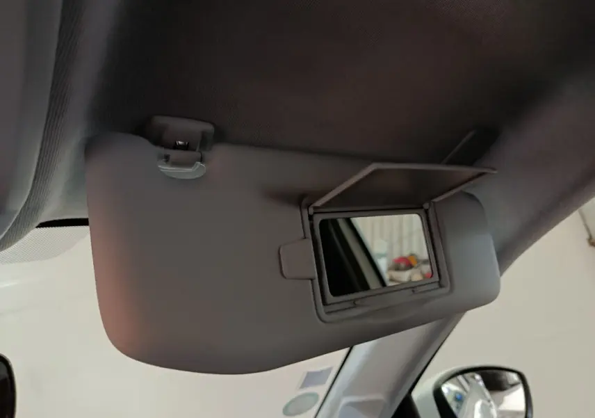 Vue intérieure rapprochée du pare-soleil côté conducteur avec miroir ouvert dans une Peugeot 208 blanche électrique.