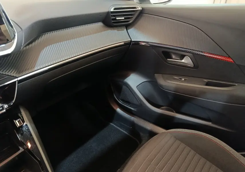 Vue intérieure côté passager de la Peugeot 208 Electrique Active Business 2020 avec tableau de bord noir et détails rouges.