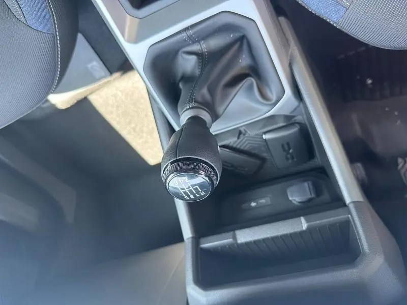 Gros plan sur le levier de vitesses manuel noir du Dacia Duster blanc, avec console centrale et prises USB visibles.