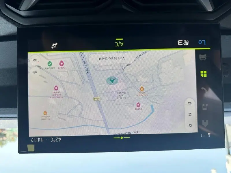 Écran tactile central du Dacia Duster blanc 2025 affichant la navigation GPS et les réglages climatisation en mode automatique.