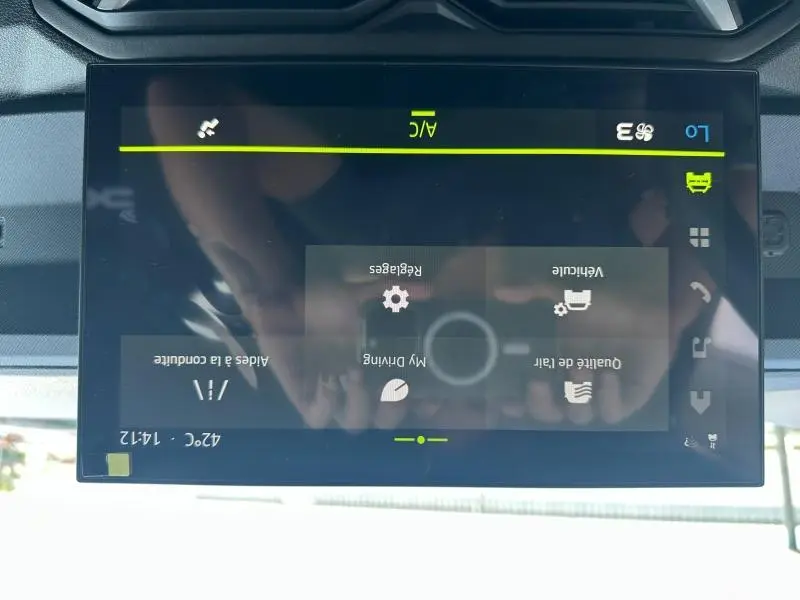 Écran tactile central du tableau de bord du Dacia Duster blanc 2025 affichant les réglages de conduite et climatisation.