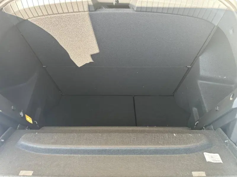 Coffre vide vu de l'arrière d'un Dacia Duster blanc 2025, montrant le plancher et les parois intérieures noires.