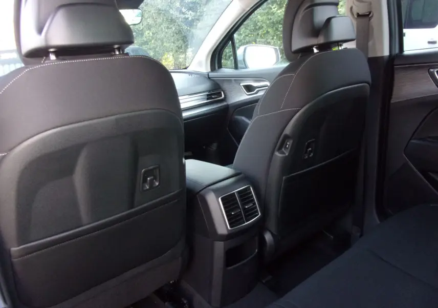 Vue intérieure arrière du Kia Sportage gris perle, montrant les sièges avant noirs et la console centrale avec aérateurs.