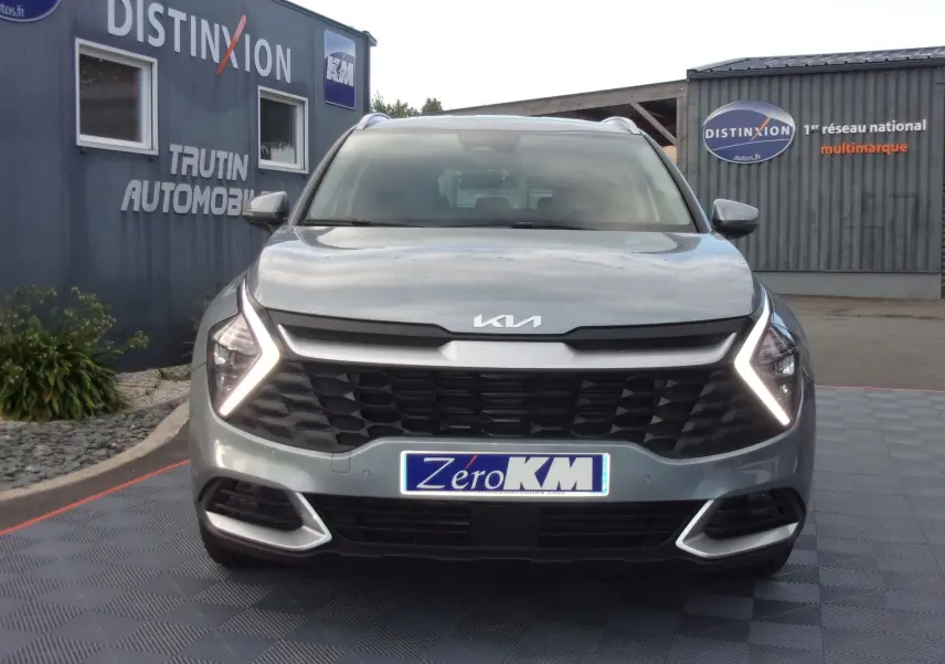 Vue frontale d'un KIA SPORTAGE gris perle 2025 avec phares LED en forme de V et calandre noire distinctive.