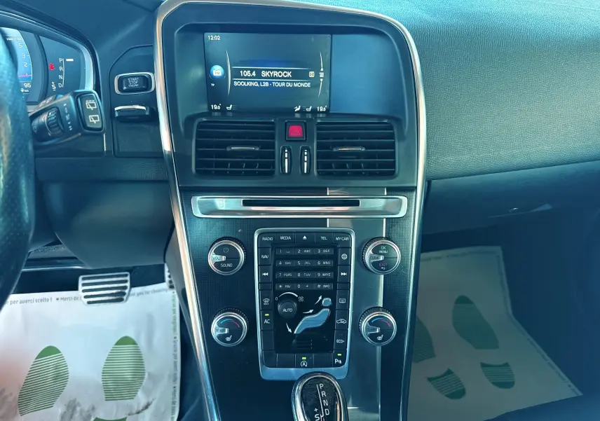 Vue rapprochée du tableau de bord et console centrale noire du Volvo XC60 gris, avec écran radio affichant Skyrock.