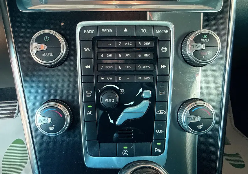 Vue rapprochée du panneau central de commande du Volvo XC60 gris 2016, avec réglages climatisation et audio.