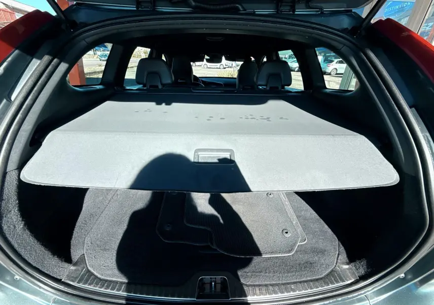 Coffre ouvert d'un Volvo XC60 gris 2016, vue arrière montrant la plage arrière et tapis de sol noir.