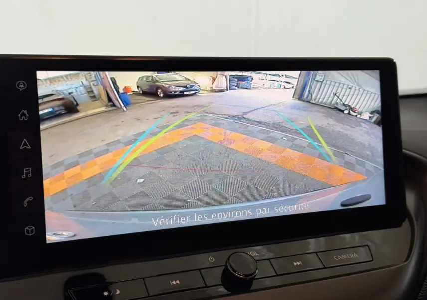Écran tactile intérieur montrant la caméra de recul du Nissan Juke gris clair, avec lignes de guidage colorées.