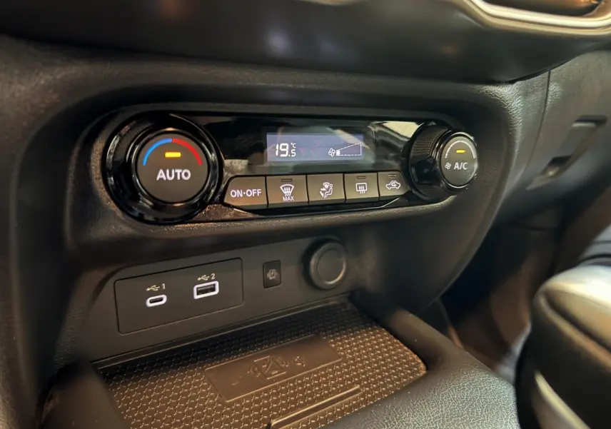 Détail de la console centrale noire du Nissan Juke 2025, montrant la climatisation automatique et ports USB.