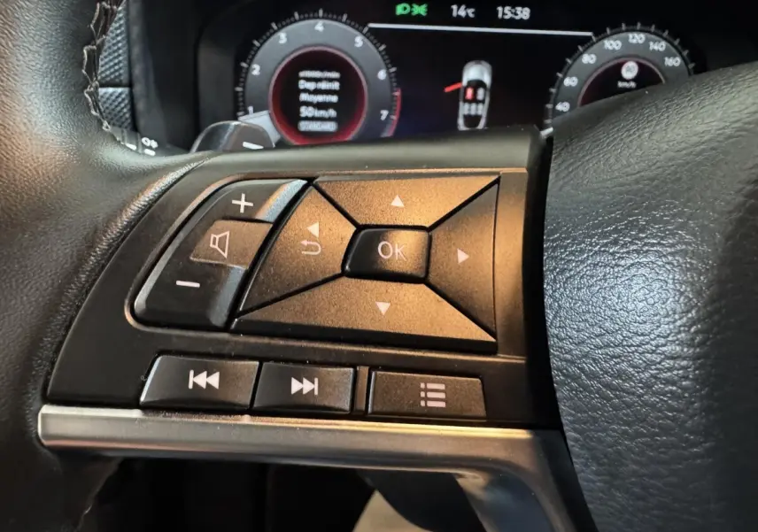 Gros plan sur les commandes multifonctions côté gauche du volant cuir du Nissan Juke gris clair 2025.