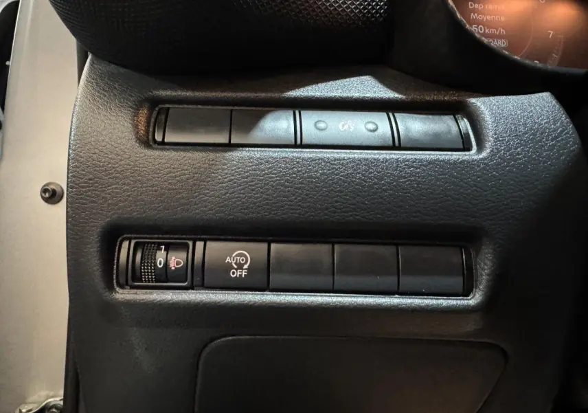 Gros plan sur les commandes de réglage des phares et d'activation automatique dans un Nissan Juke gris clair 2025.