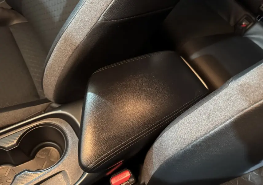 Gros plan sur l'accoudoir central en cuir noir entre les sièges arrière gris foncé du Nissan Juke 2025.