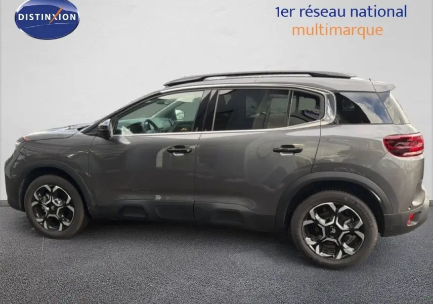 Citroën C5 Aircross Hybrid gris platinium en 3/4 avant droit avec jantes bicolores et barres de toit noires.