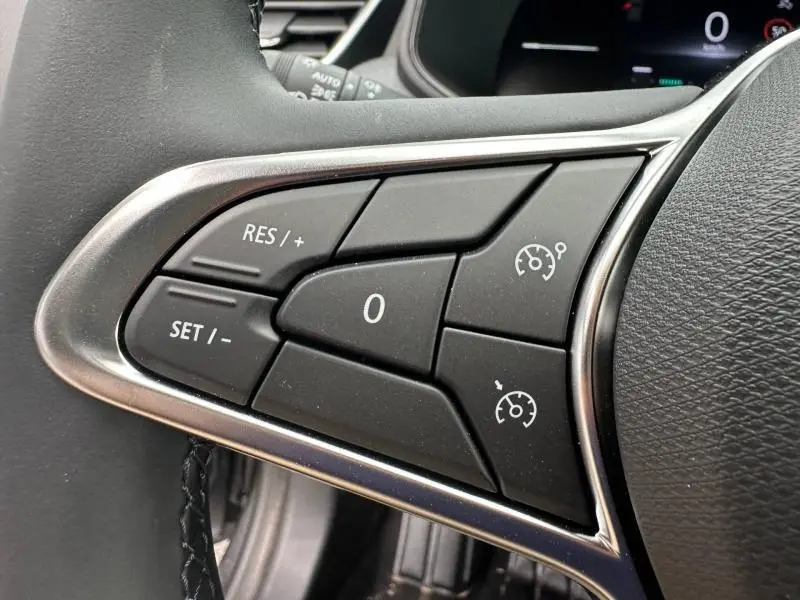 Gros plan sur les commandes de régulateur de vitesse au volant d'une Renault Clio gris 2025, version essence boîte manuelle.
