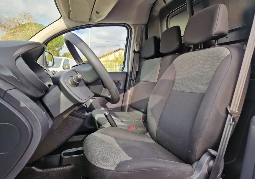 Vue intérieure côté conducteur du Renault Kangoo 2021, sièges tissu gris et volant noir, avec levier de vitesse manuel visible.