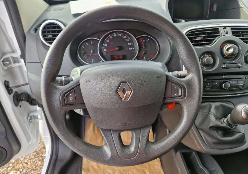 Vue intérieure centrée sur le volant noir du Renault Kangoo blanc 2021 avec tableau de bord et levier de vitesse manuel.